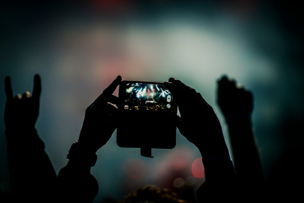Spectateur filmant un concert avec un smartphone