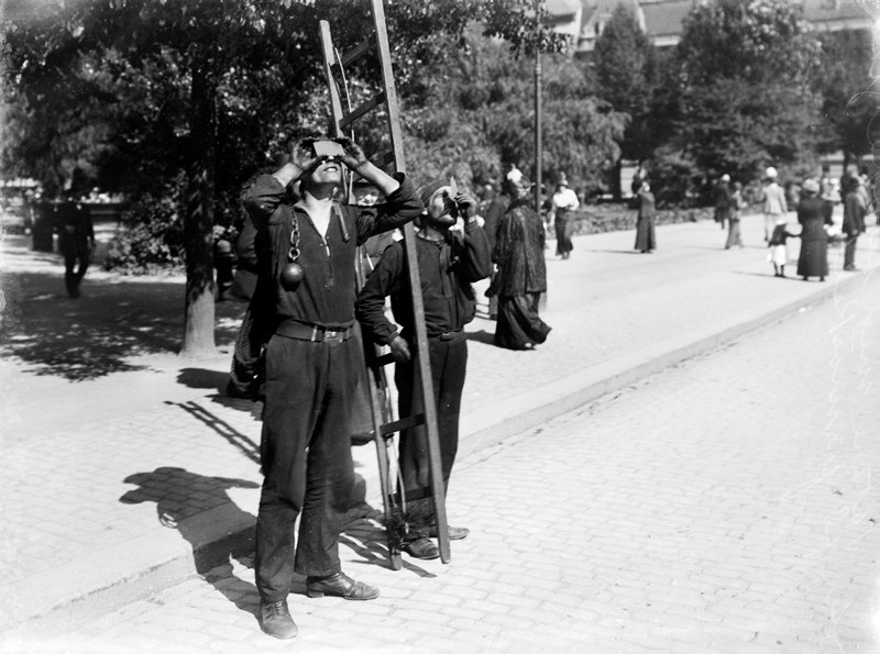 Solförmörkelse i Stockholm. Två sotare står på gatan och ti