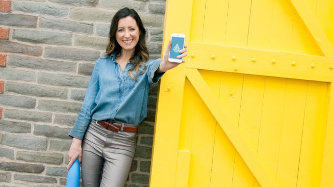 Femme devant une porte jaune brandissant un téléphone