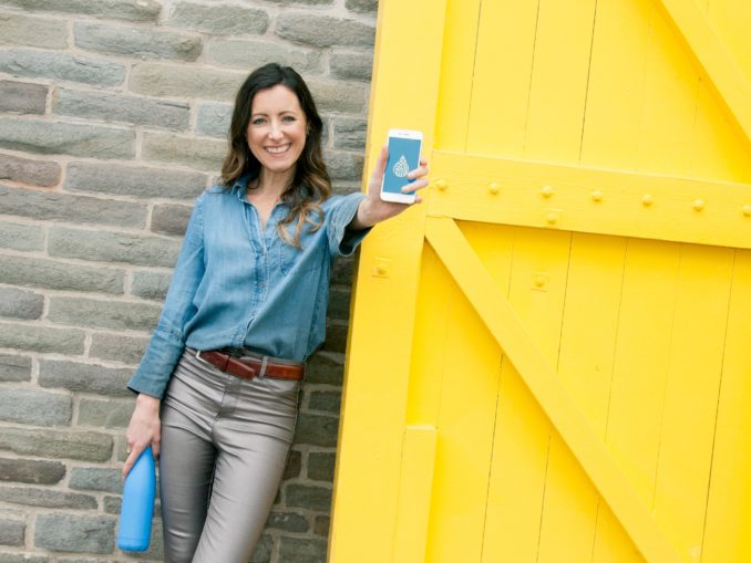 Femme devant une porte jaune brandissant un téléphone