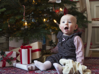 Enfant assis devant un sapin de Noël