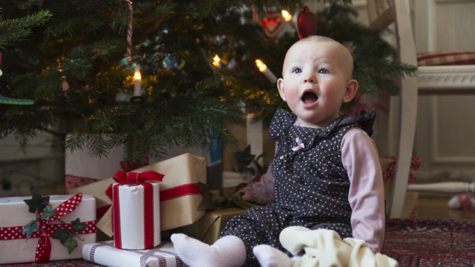 Enfant assis devant un sapin de Noël