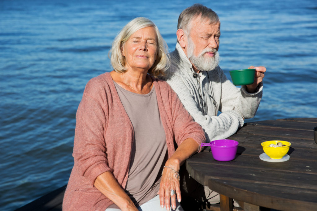 Couple de retraités mangeant au bord de l'eau